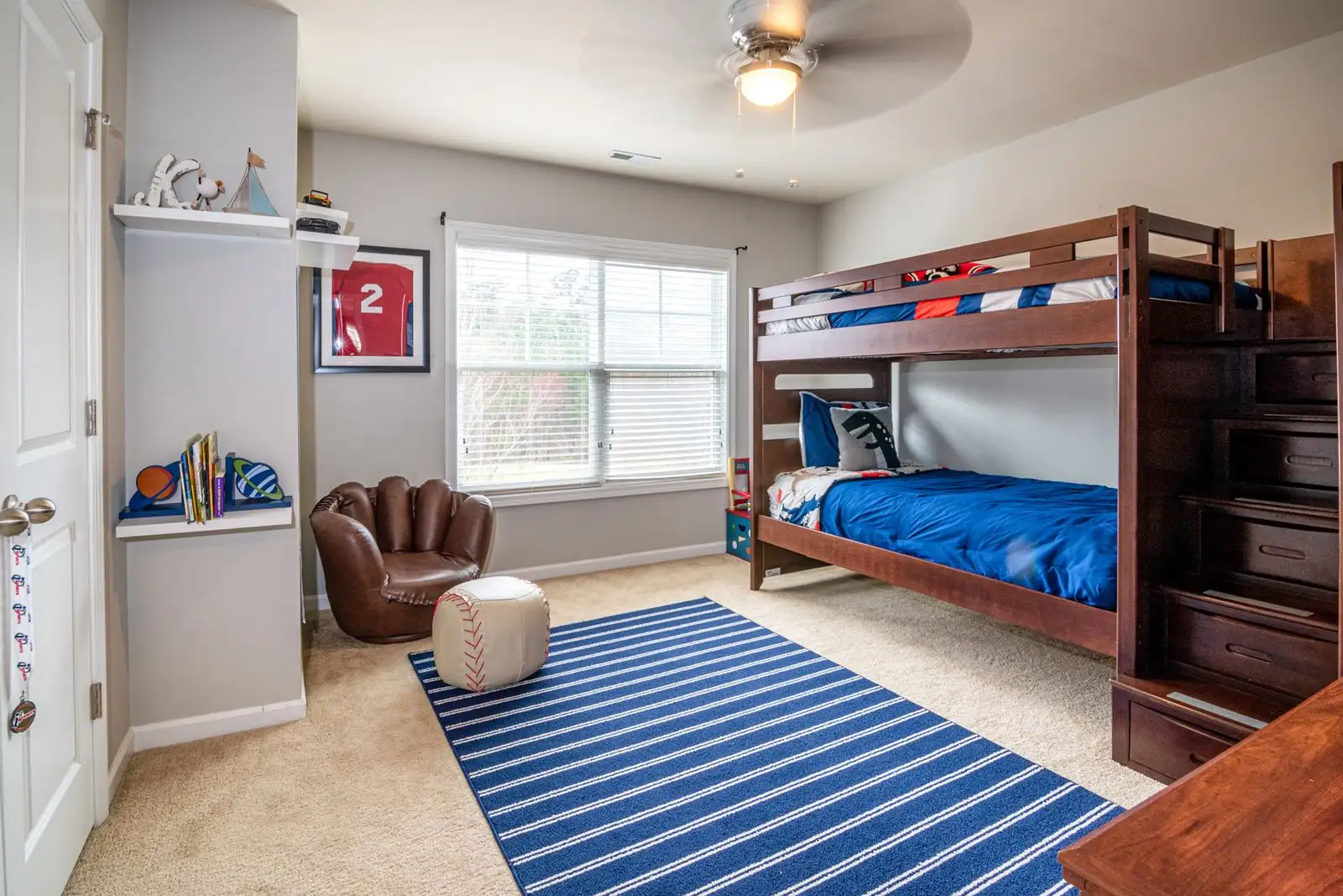 Child's bedroom with a wooden bunk bed, blue bedding and a striped rug