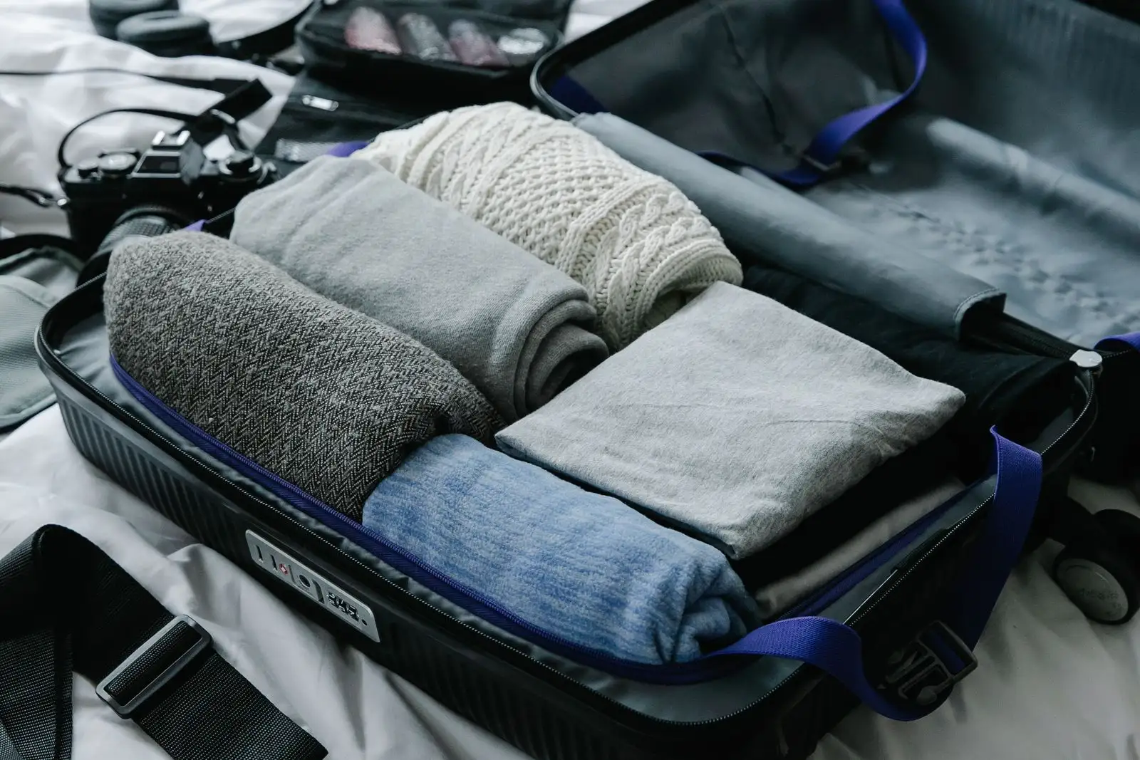 Open suitcase with neatly rolled clothes, packed for a move abroad